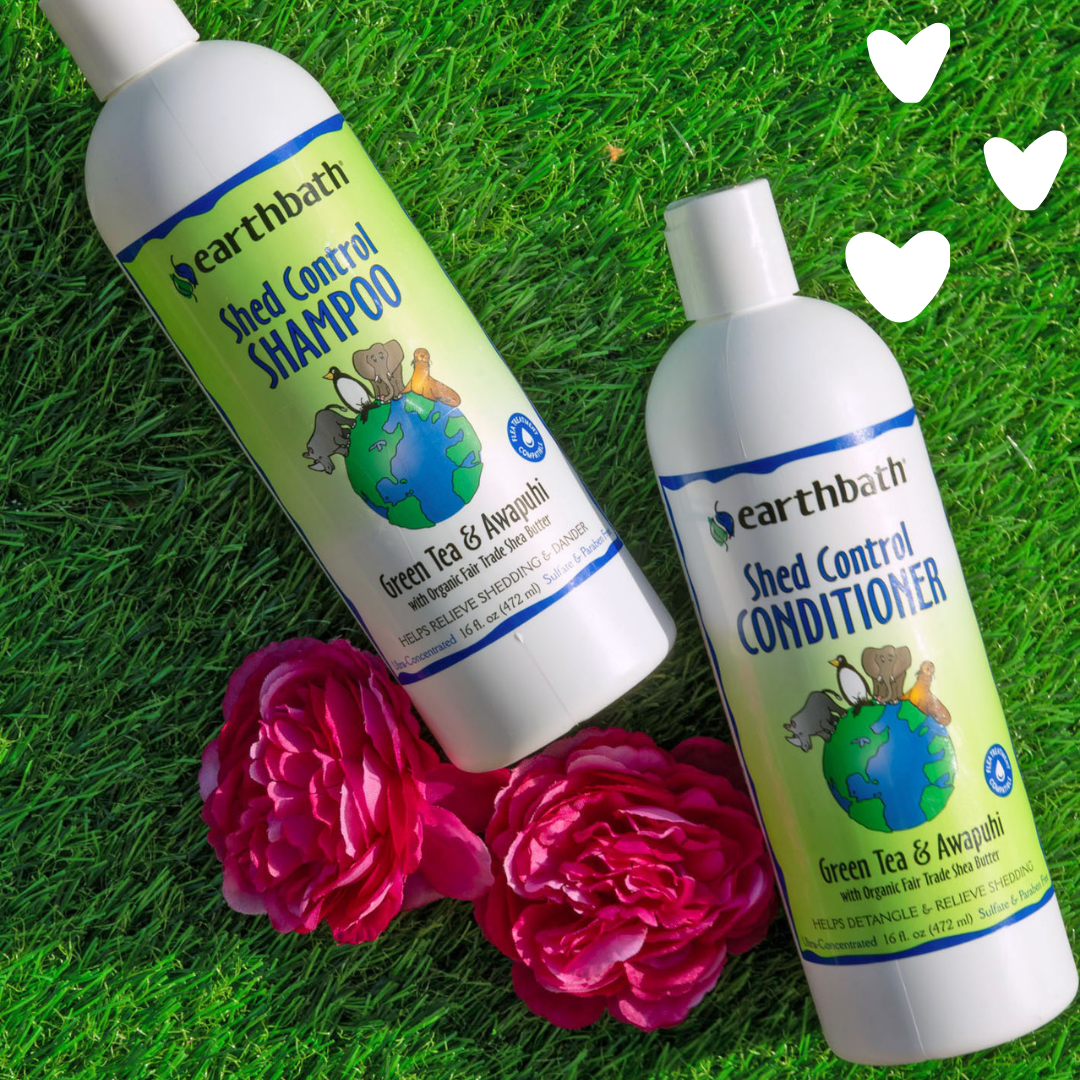 earthbath Shed Control Shampoo and Conditioner bottles on grass with pink flowers